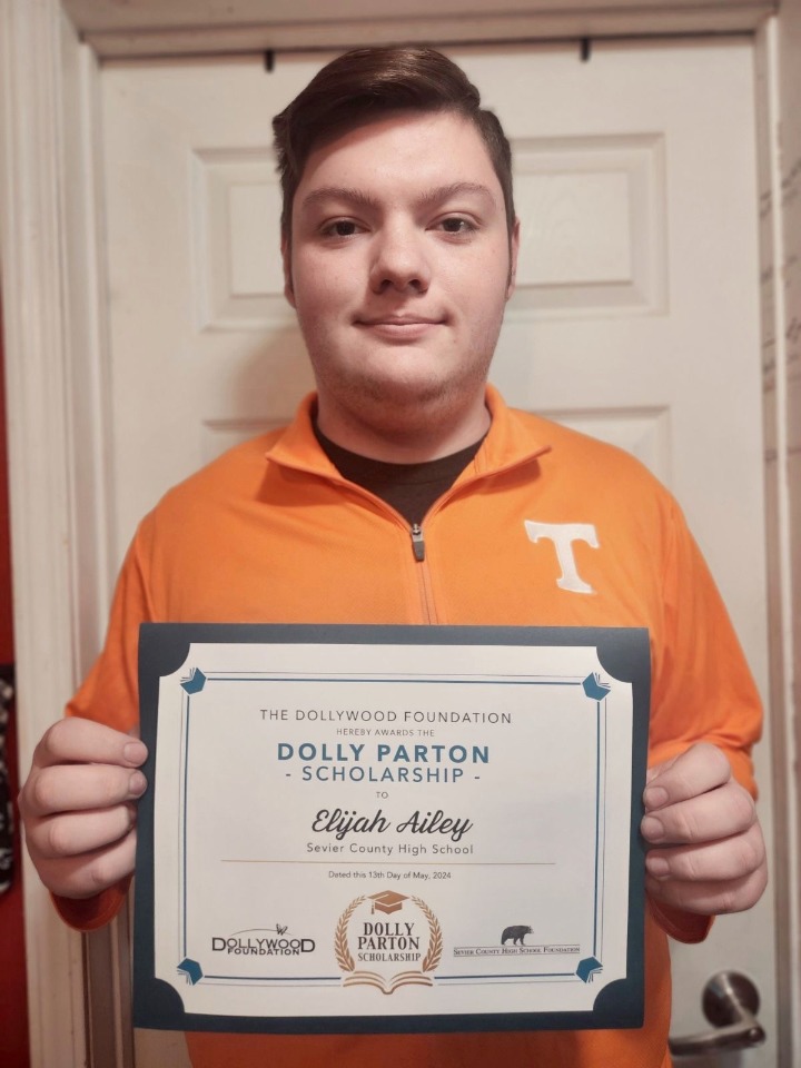 Elijah Ailey holding his certificate for the Dolly Parton Scholarship